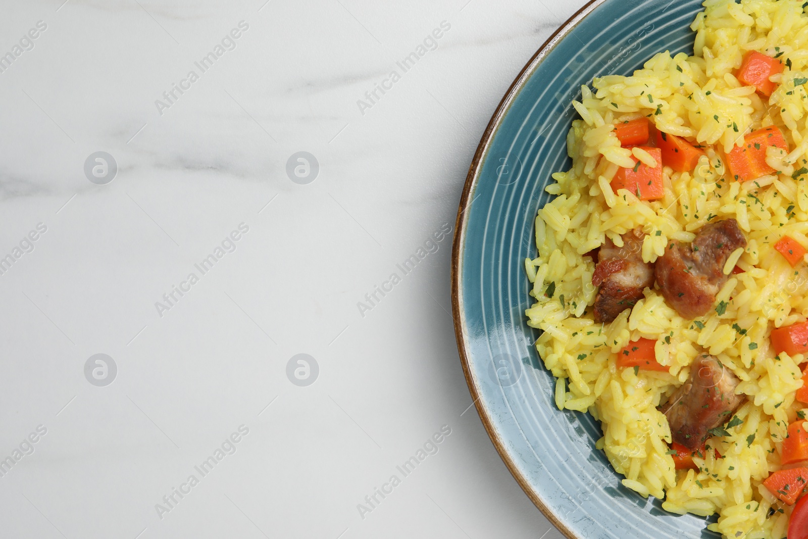 Photo of Delicious pilaf with meat on white marble table, top view. Space for text