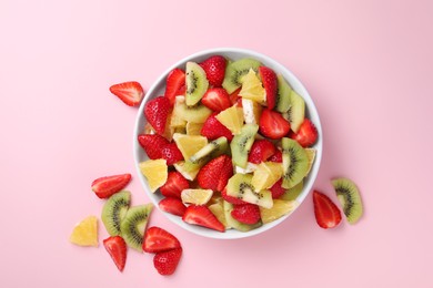 Photo of Yummy fruit salad in bowl and ingredients on pink background, flat lay