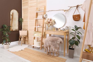 Stylish room interior with modern wooden dressing table near white wall