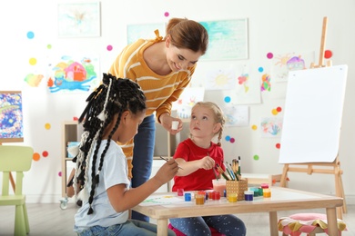 Photo of Children with female teacher at painting lesson indoors