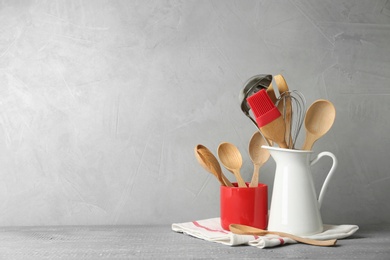 Different kitchen utensils on wooden table against light grey background. Space for text