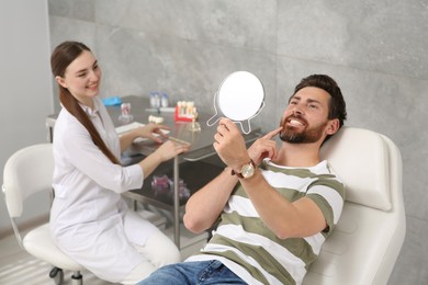 Man looking at his new dental implants in mirror indoors