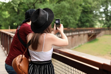 Photo of Young woman taking photo in beautiful park