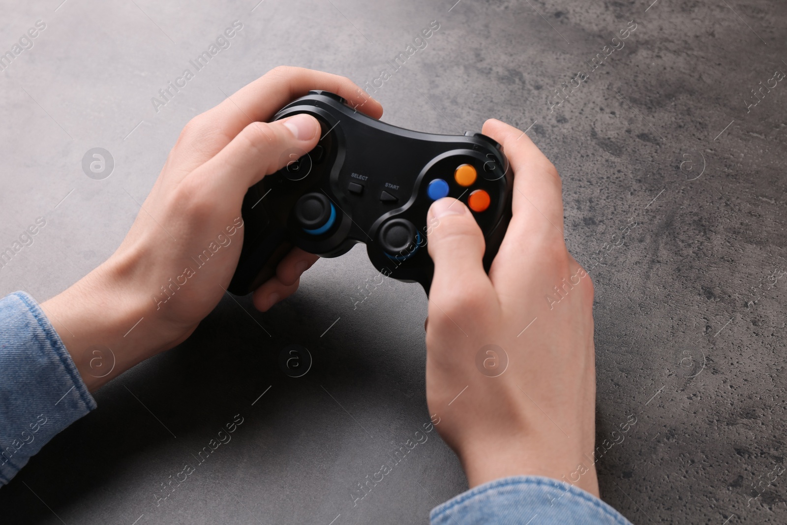 Photo of Man using wireless game controller at grey table, closeup