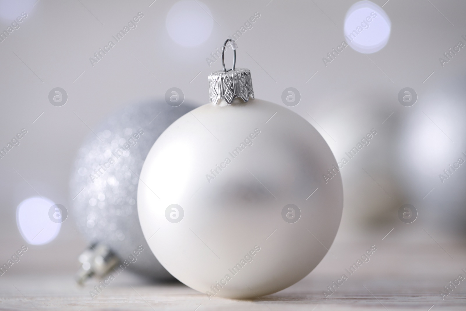 Photo of Beautiful Christmas balls on table against blurred festive lights