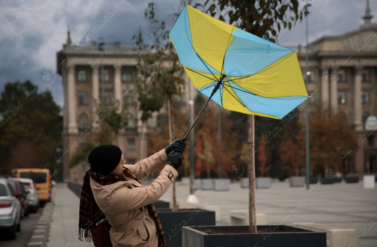 Photo of Man with colorful umbrella caught in gust of wind on street