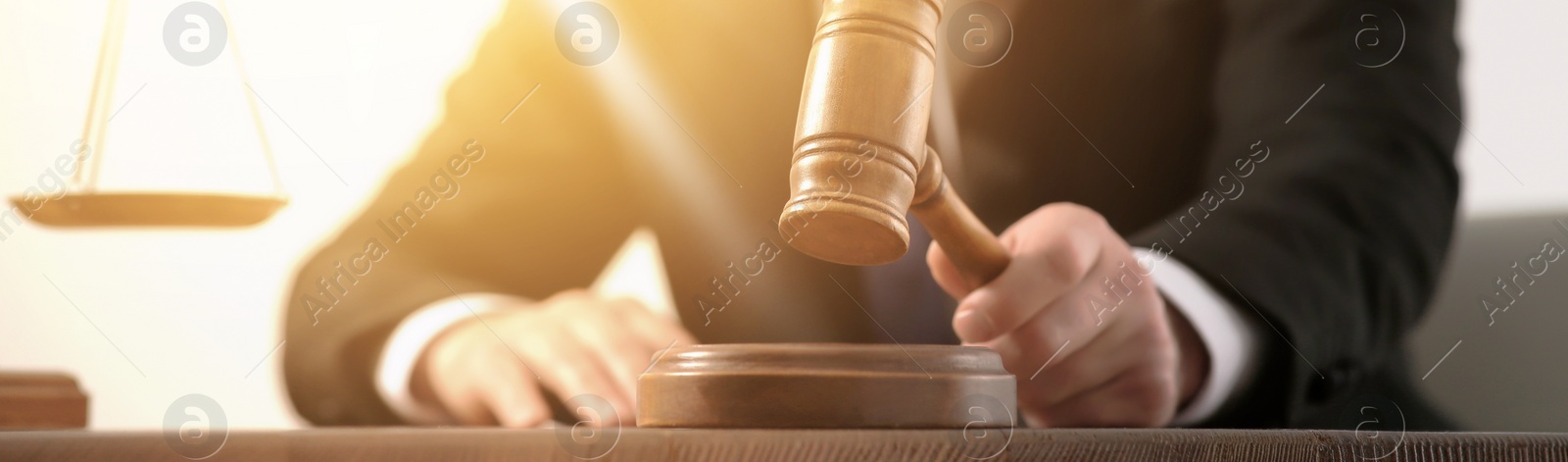 Image of Law and justice. Judge with gavel at wooden table, closeup. Banner design