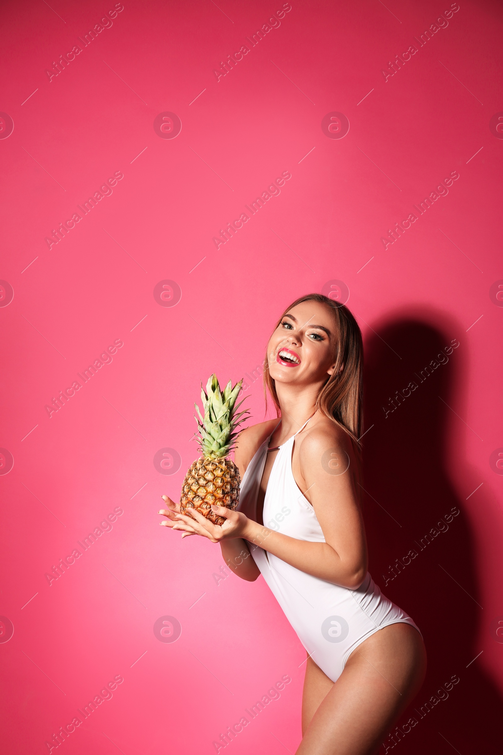 Photo of Pretty sexy woman in stylish bikini with pineapple on color background, space for text