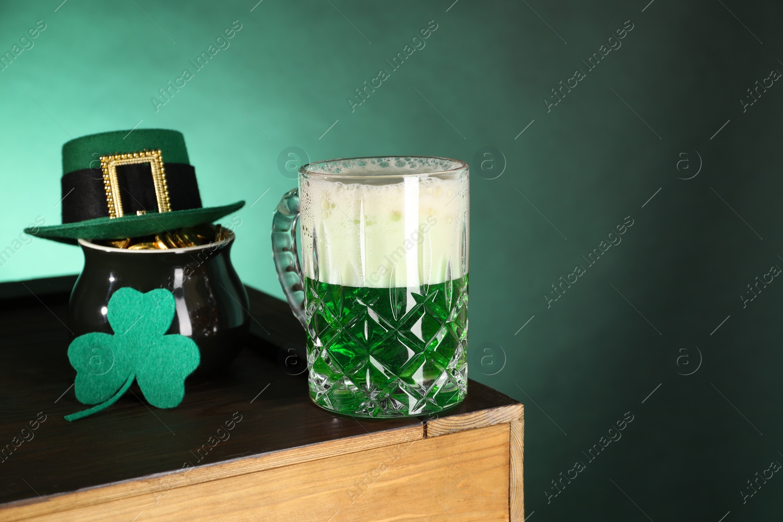 Photo of St. Patrick's day celebration. Green beer, leprechaun hat, pot of gold and decorative clover leaf on wooden table. Space for text