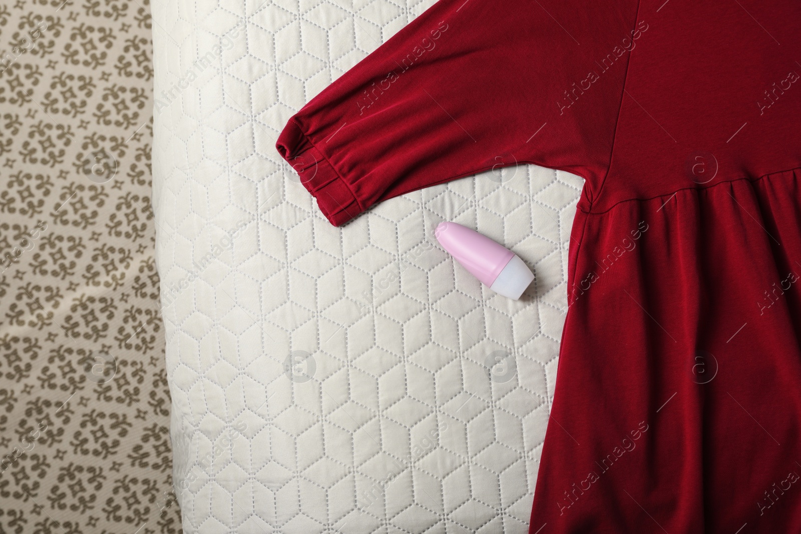 Photo of Female roll-on deodorant and clothes on bed, top view. Space for text