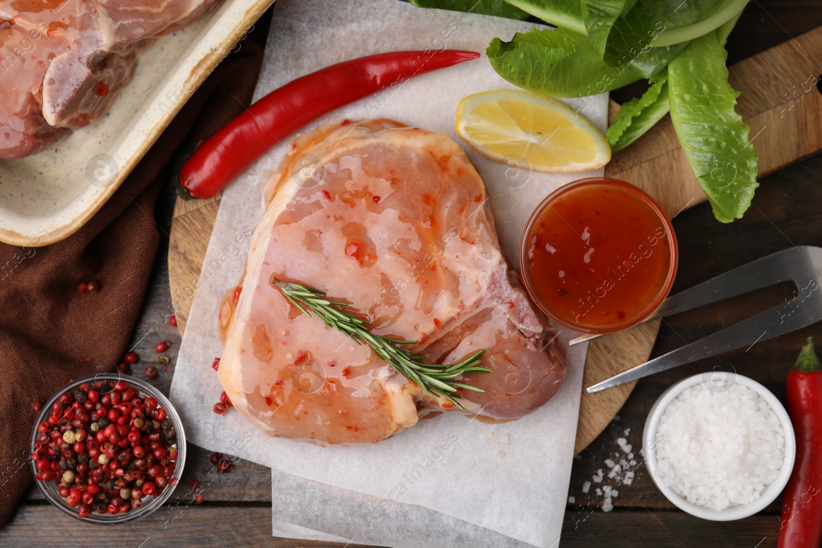 Photo of Flat lay composition with raw marinated meat, lemon, rosemary and spices on wooden table