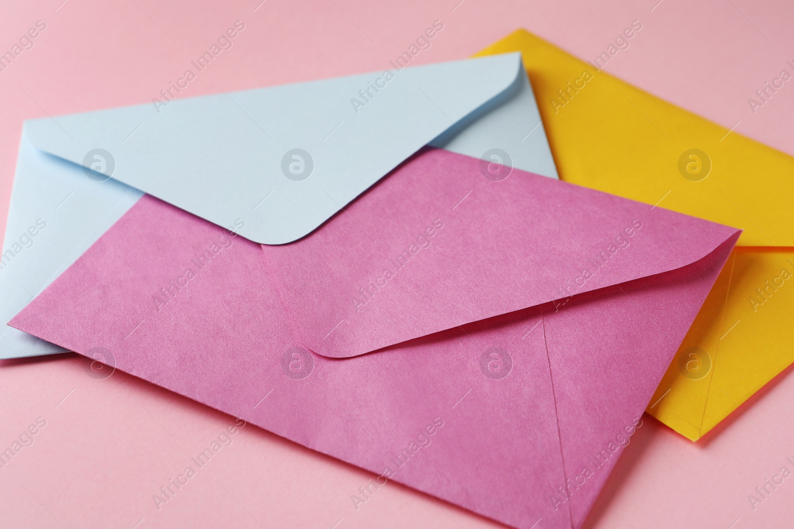 Photo of Colorful paper envelopes on pink background, closeup