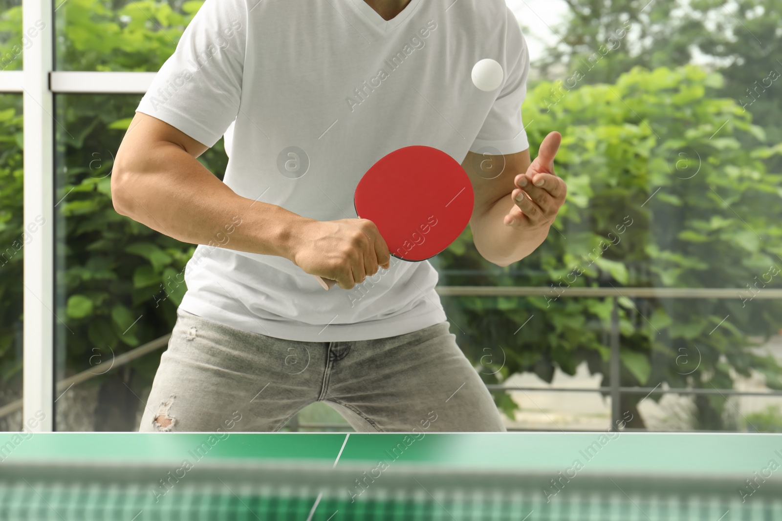 Photo of Man playing ping pong indoors, closeup view