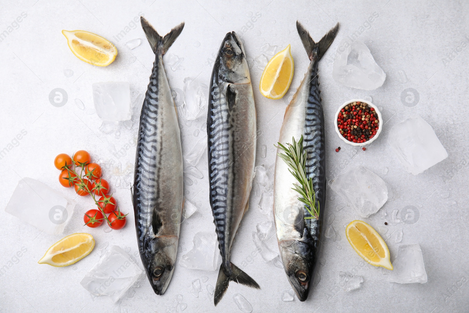 Photo of Raw mackerel, tomatoes and lemons on light gray table, flat lay