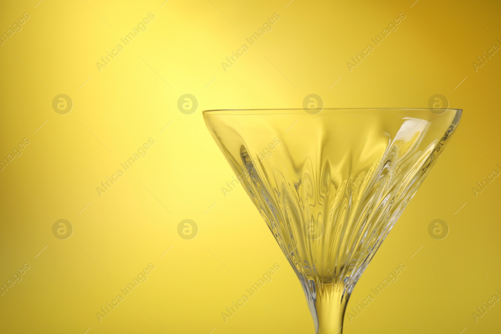 Photo of Elegant empty martini glass on yellow background, closeup. Space for text