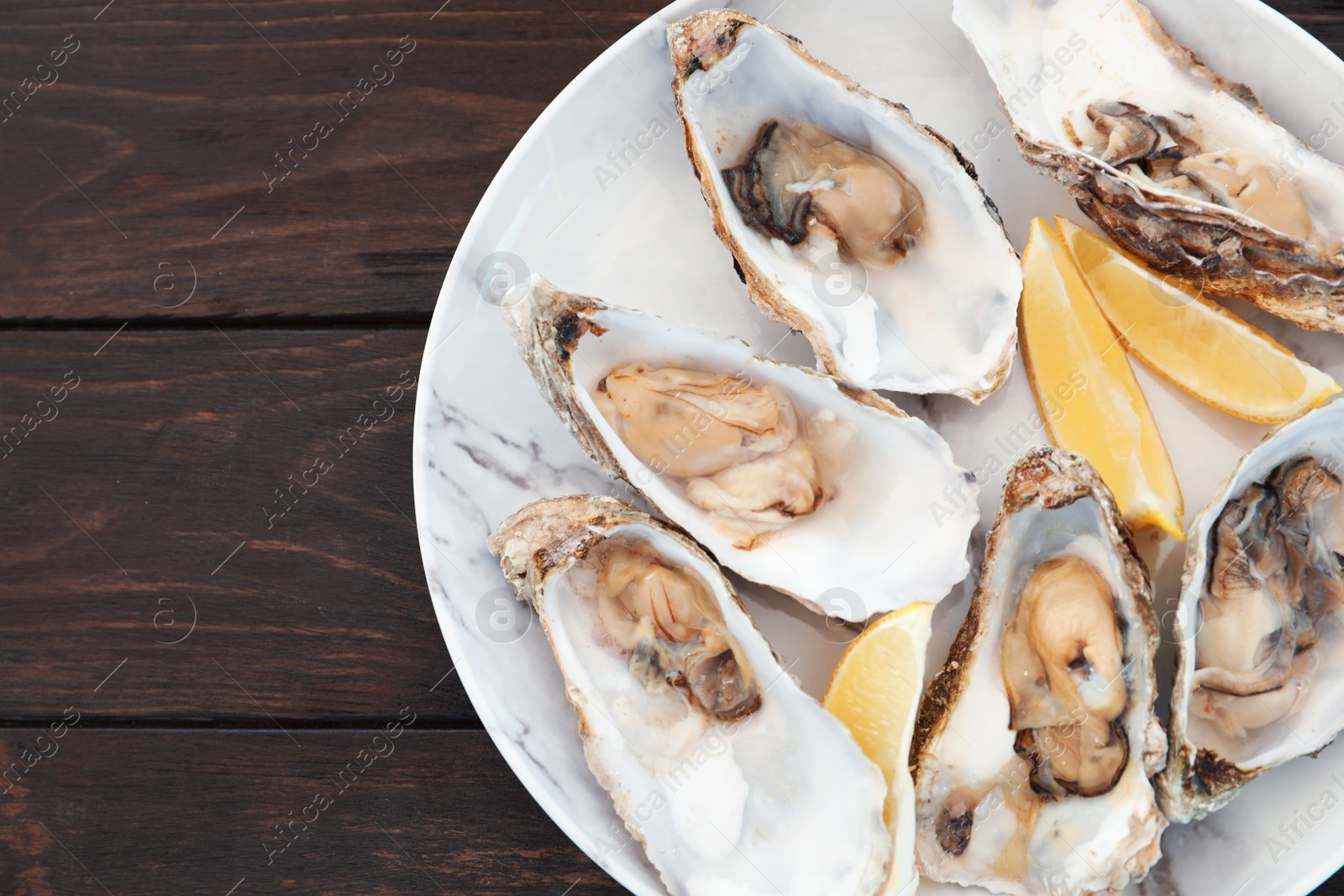 Photo of Fresh oysters with cut juicy lemon and space for text on table, top view