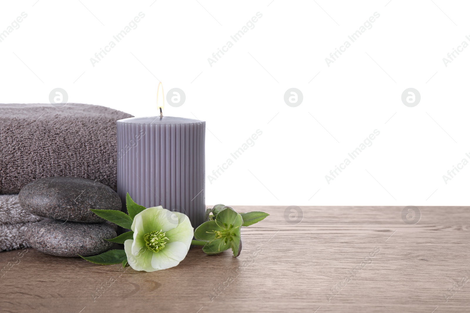 Photo of Composition with spa stones and candle on wooden table against white background