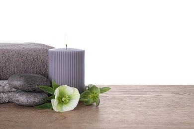 Composition with spa stones and candle on wooden table against white background