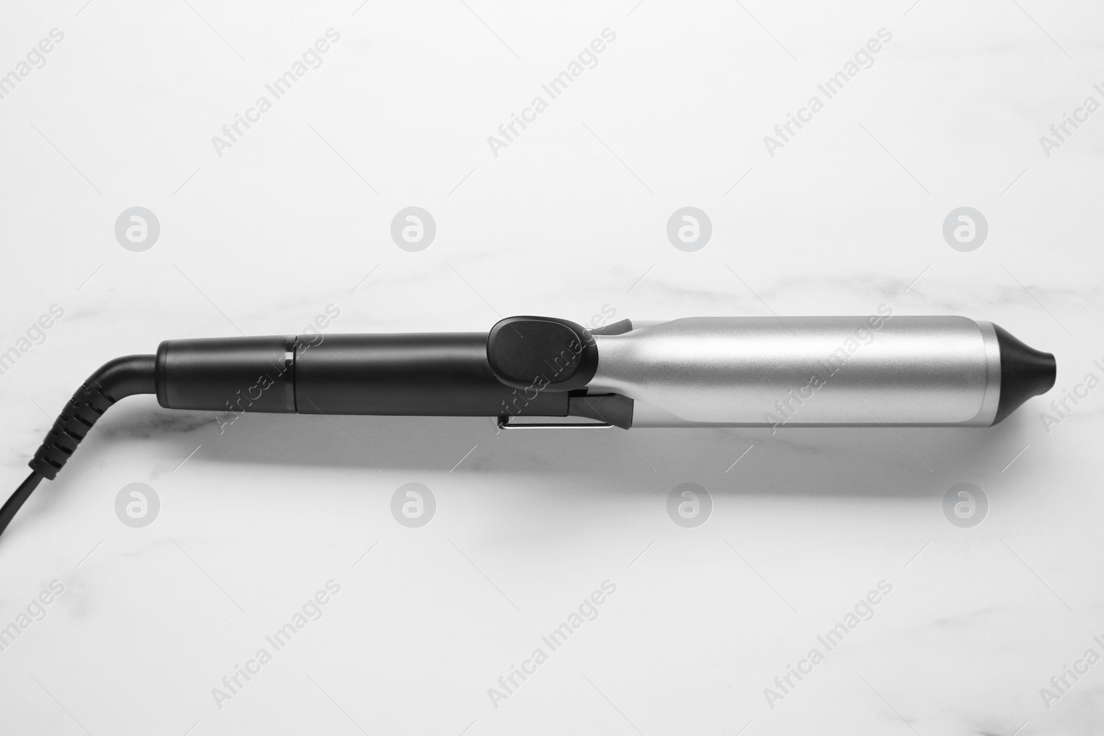 Photo of Hair curling iron on white marble background
