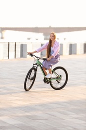 Photo of Young woman riding bicycle in city on sunny day