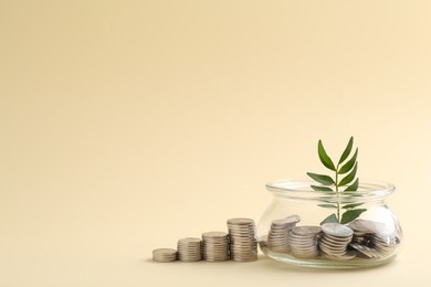 Financial savings. Coins, twig and glass jar on beige background, space for text