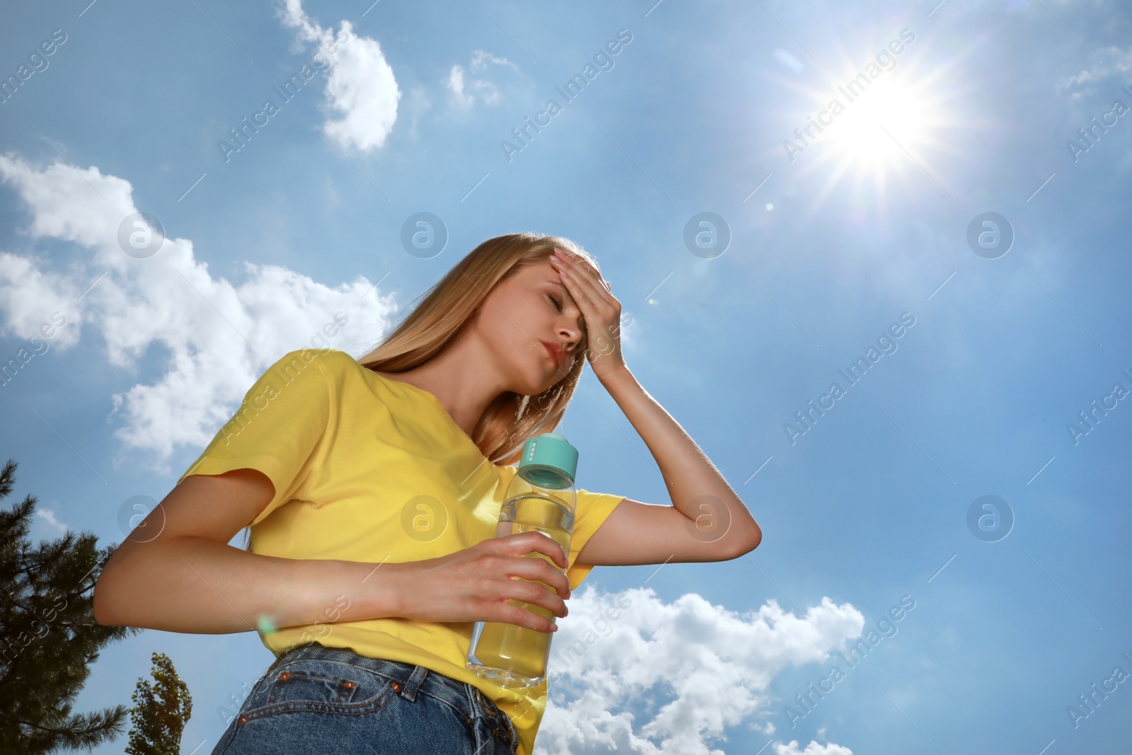 Photo of Woman with bottle of water suffering from heat stroke outdoors