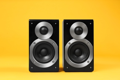Photo of Modern powerful audio speakers on yellow background