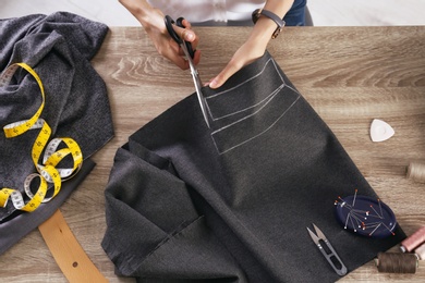 Tailor working with cloth at table in atelier, top view