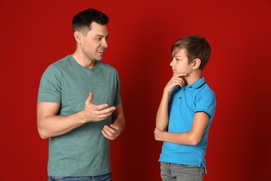 Dad talking with his son on color background