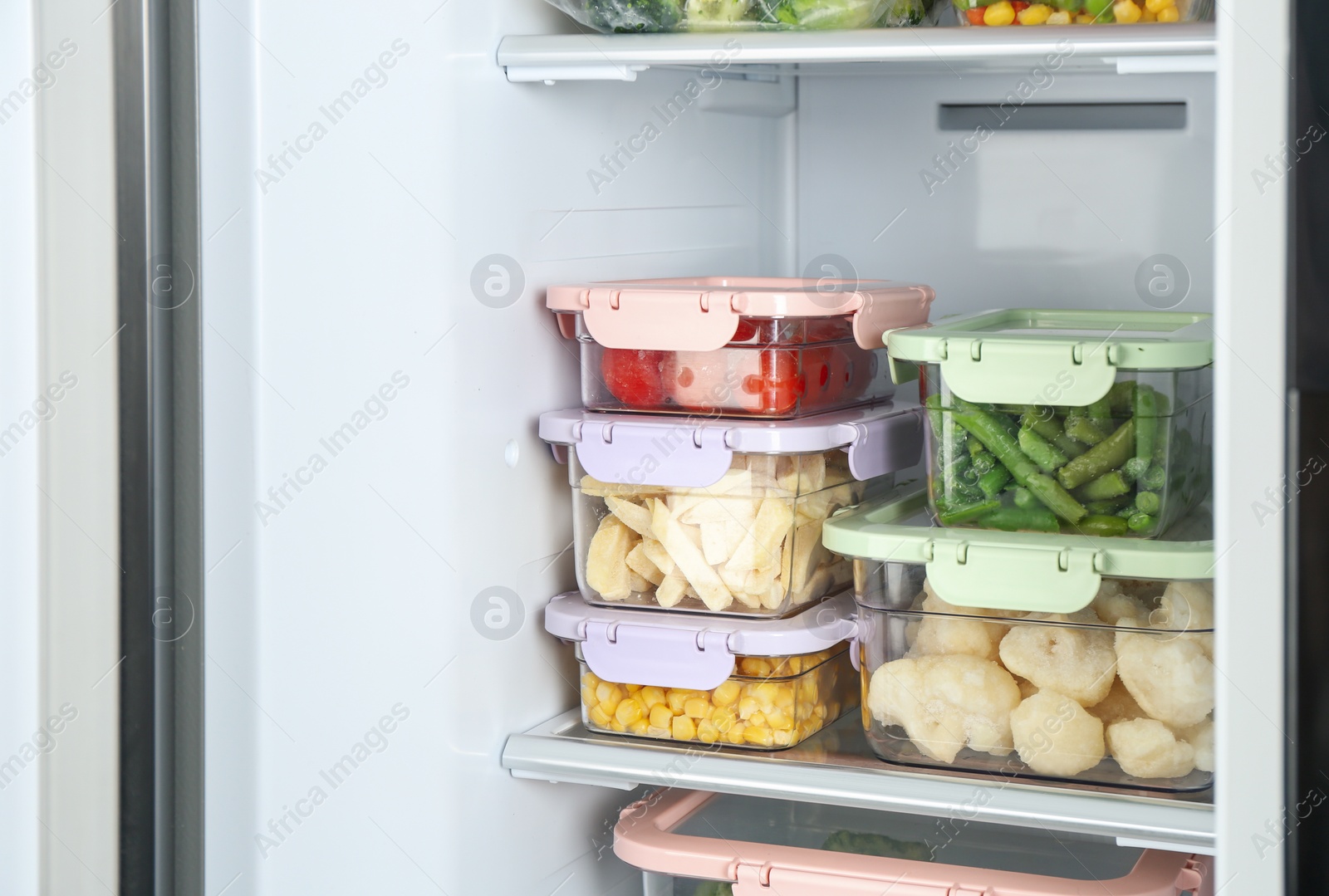 Photo of Containers with different frozen vegetables in refrigerator