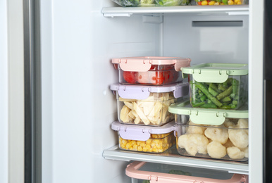 Containers with different frozen vegetables in refrigerator