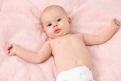 Photo of Cute little baby with cream on face on pink blanket, top view