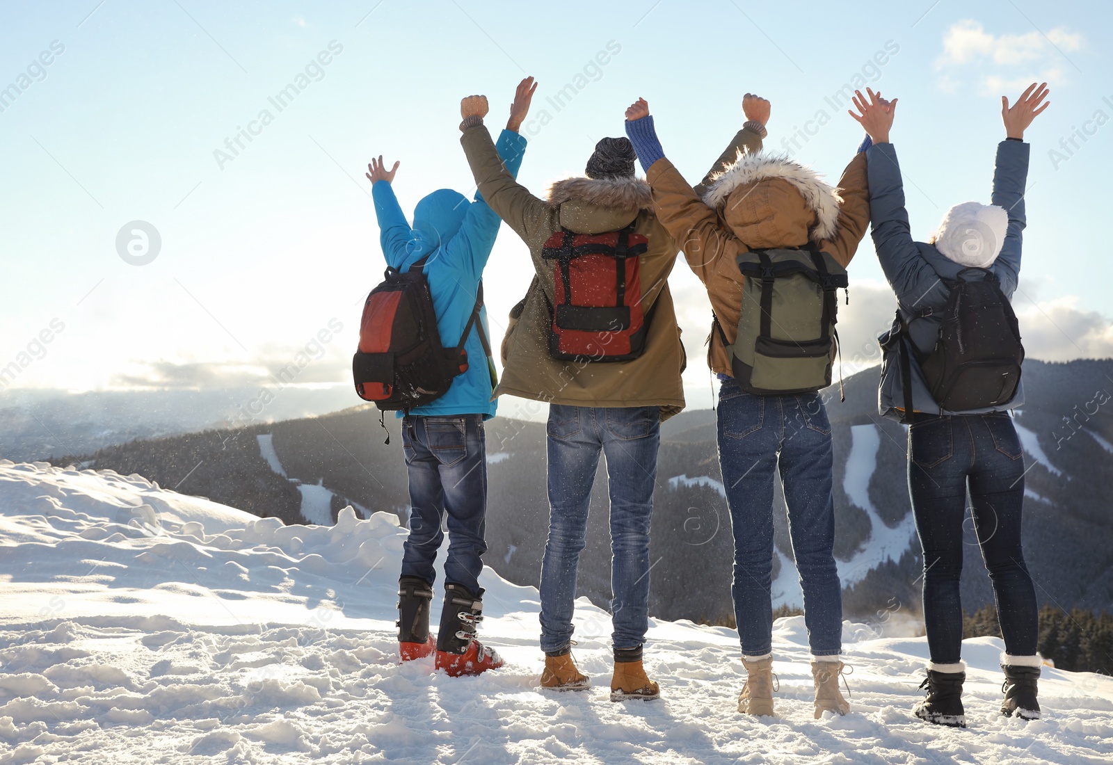 Photo of Group of excited friends with backpacks enjoying mountain view during winter vacation