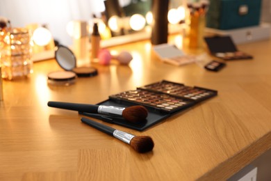 Photo of Brushes and other cosmetic products on wooden dressing table in makeup room