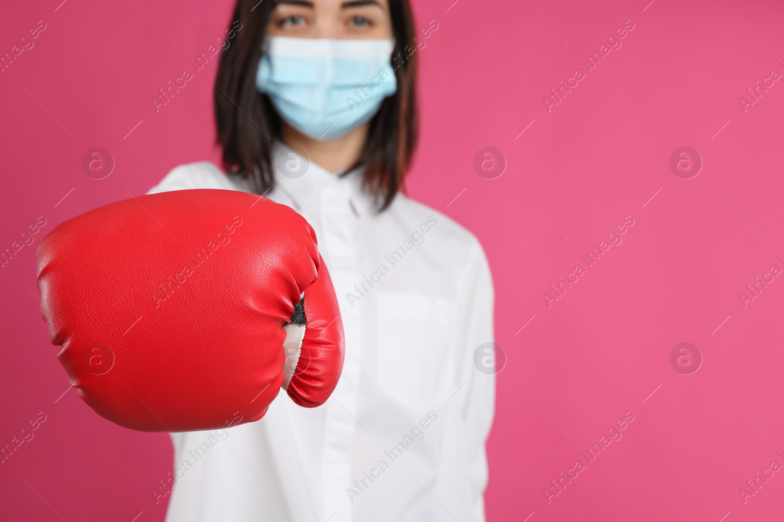 Photo of Woman with protective mask and boxing gloves on pink background, space for text. Strong immunity concept