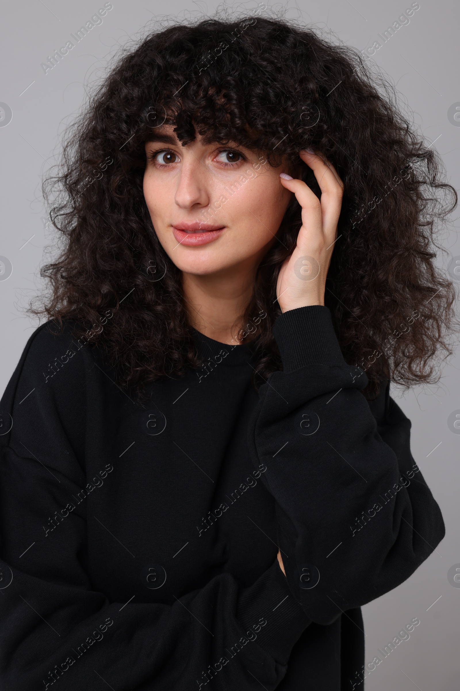 Photo of Young woman in stylish black sweater on light grey background