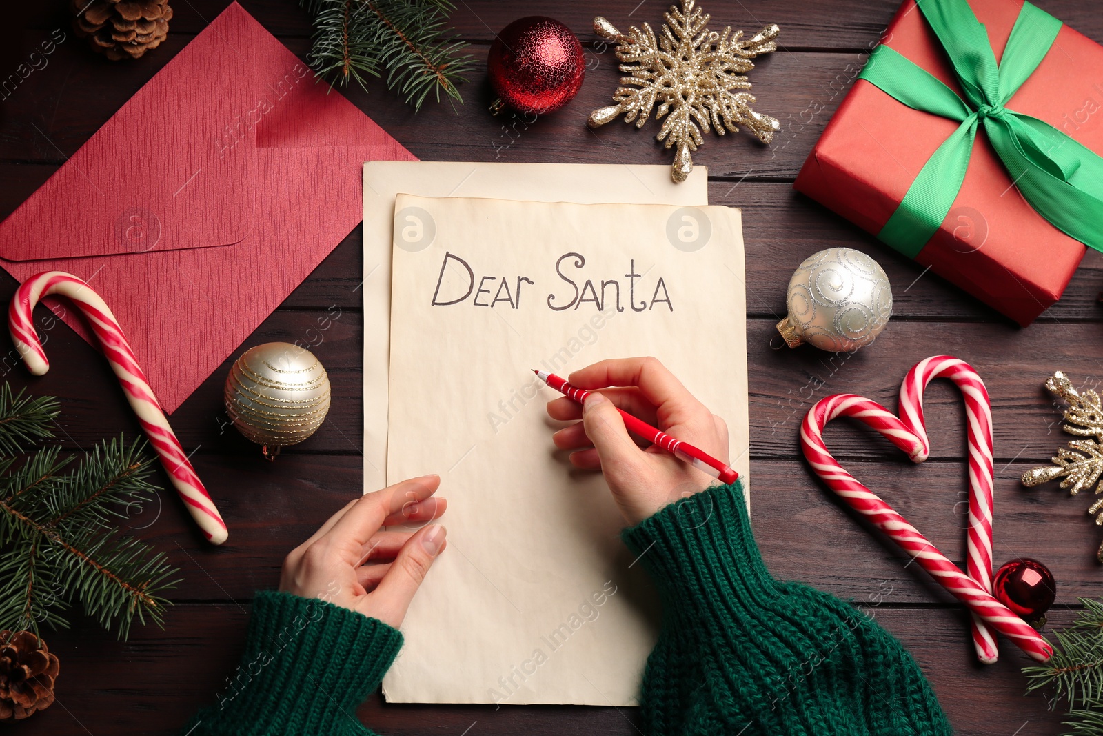 Photo of Top view of woman writing letter to Santa at wooden table, closeup