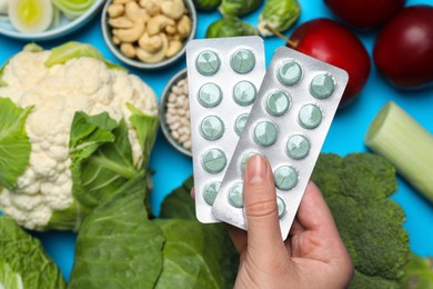 Photo of Woman holding blisters with prebiotic pills over food, top view