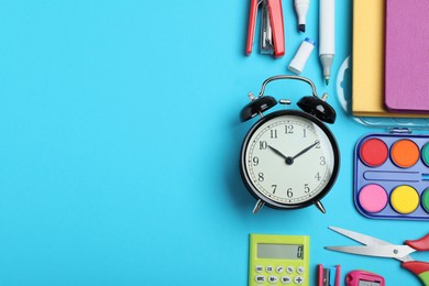 Photo of Flat lay composition with alarm clock and different stationery on light blue background, space for text. School time