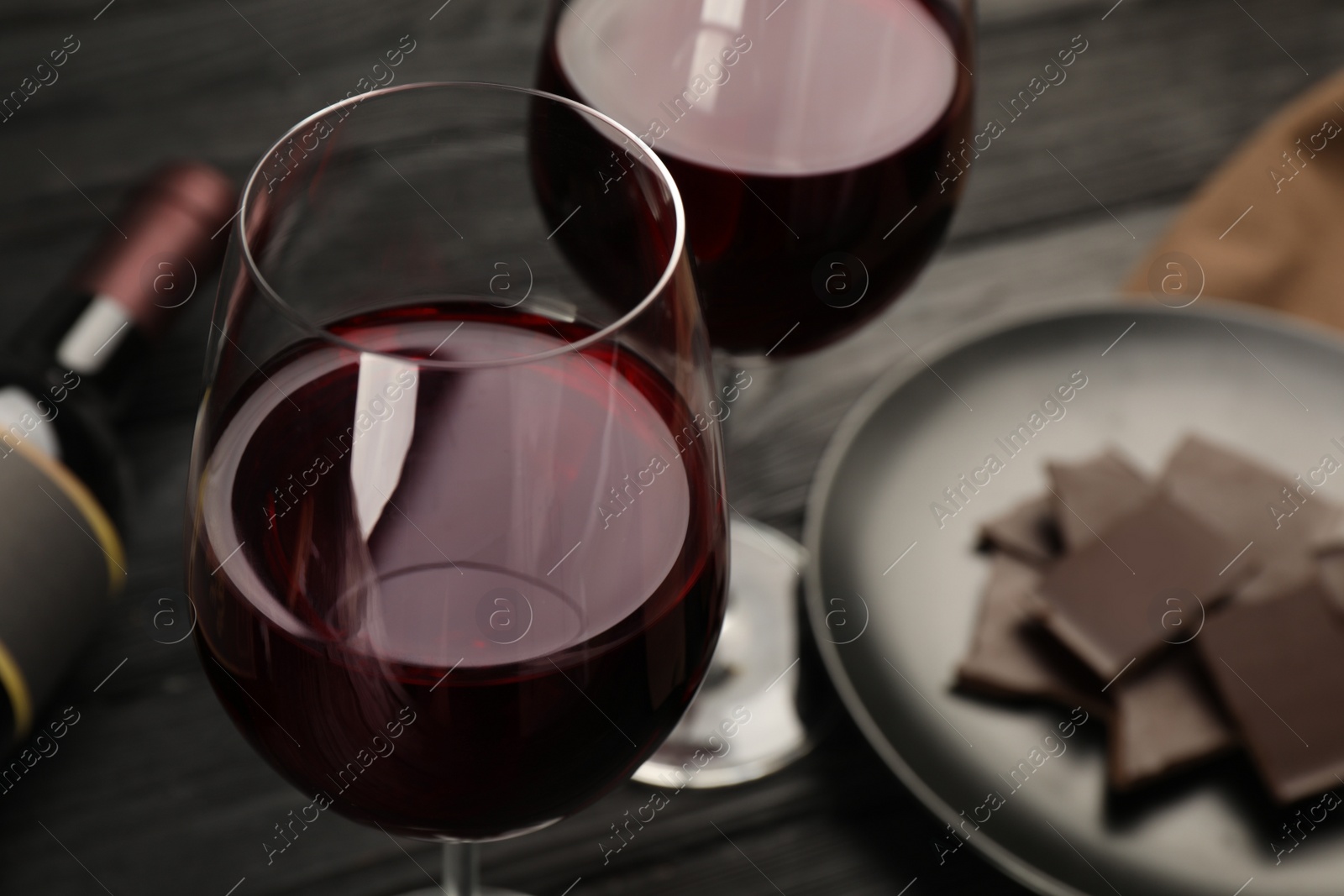 Photo of Tasty red wine and chocolate on black wooden table, closeup