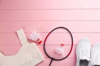 Photo of Racket, shuttlecocks and sportswear on pink wooden table, flat lay with space for text. Playing badminton