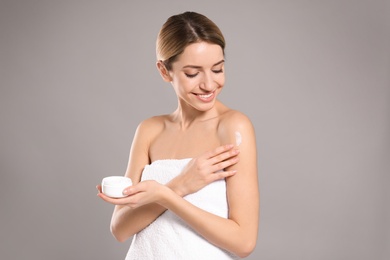 Photo of Young woman with jar of body cream on color background