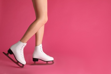 Photo of Woman in elegant white ice skates on pink background, closeup of legs. Space for text