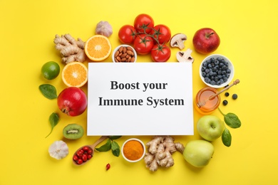 Set of natural products and paper sheet with text Boost Your Immune System on yellow background, flat lay