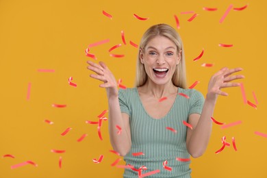 Image of Happy woman under flying confetti on orange background