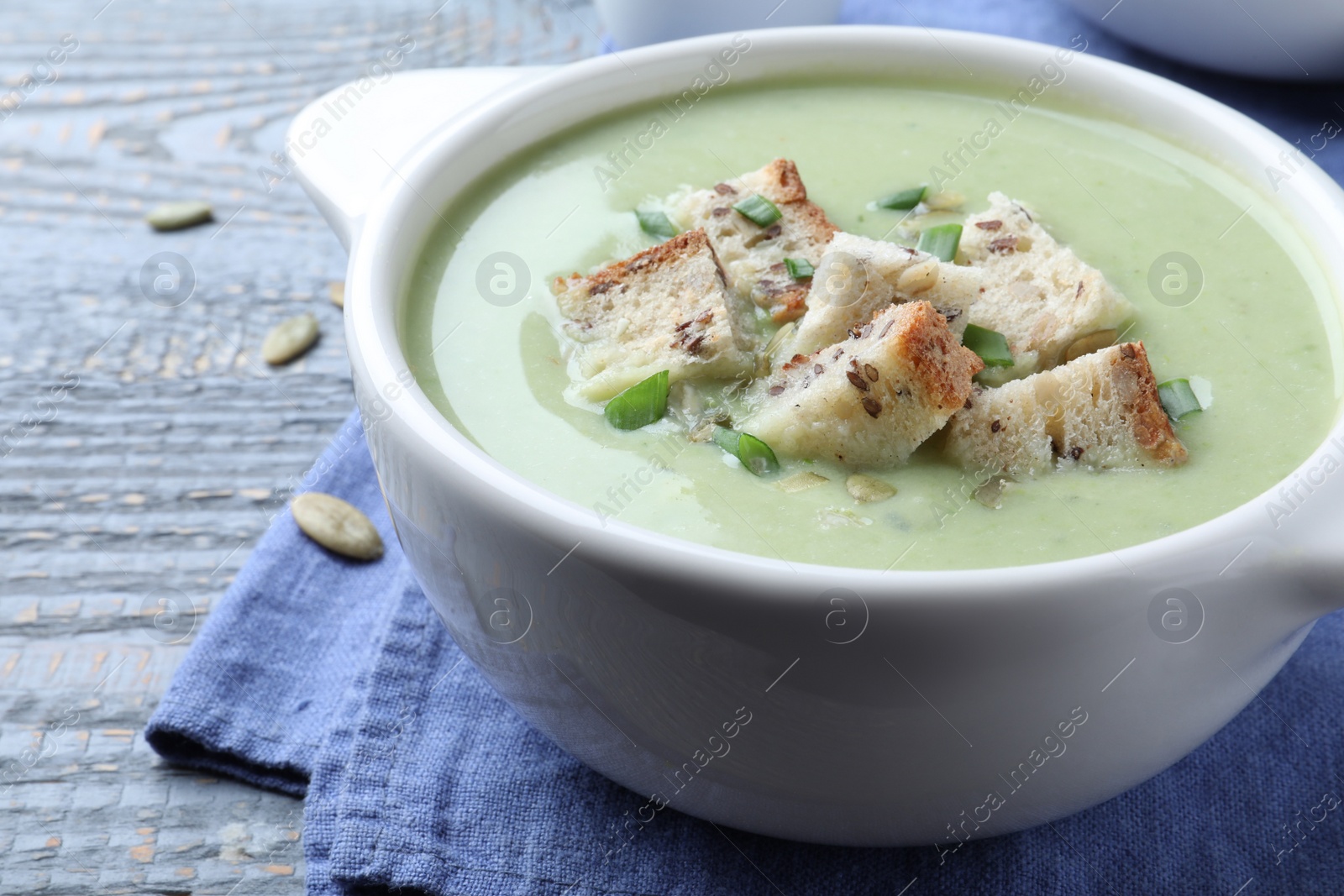 Photo of Delicious asparagus soup with croutons on grey wooden table, closeup