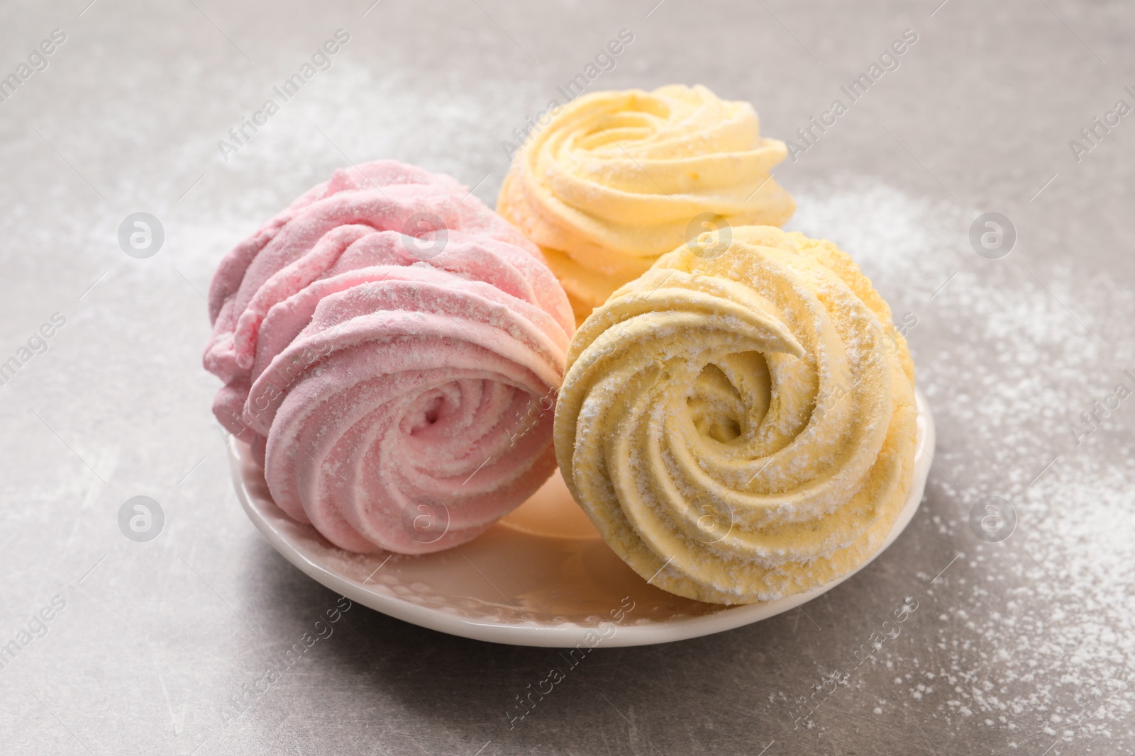 Photo of Delicious pink and yellow marshmallows on grey table