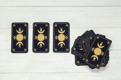 Photo of Tarot cards on white wooden table, flat lay. Reverse side
