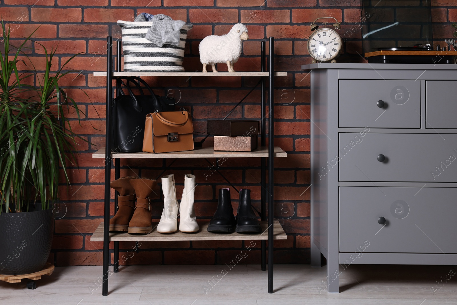 Photo of Beautiful hallway interior with chest of drawers and shoe storage bench near red brick wall