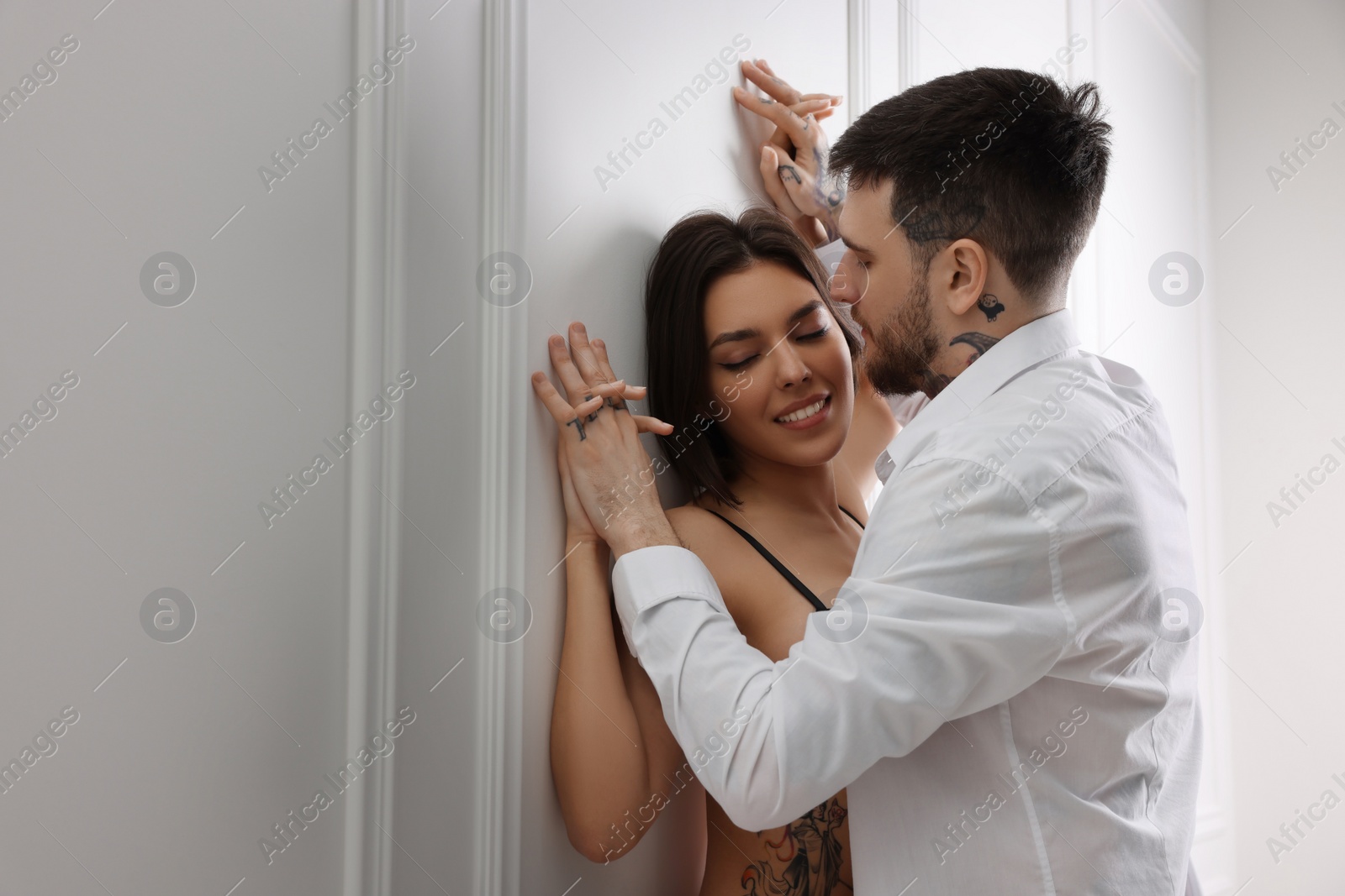 Photo of Passionate couple having sex near white wall indoors, space for text